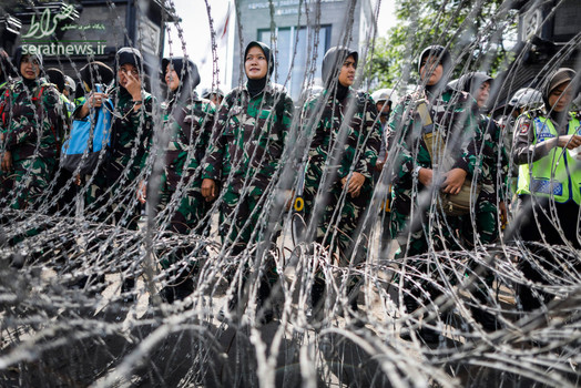 زنان پلیس اندونزی ایستاده پشت سیم خاردار در جریان برگزاری یک تظاهرات در جاکارتا