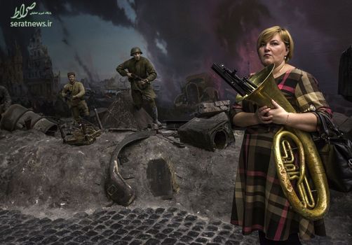 یک موسیقیدان زن مقابل صحنه ای از نبرد برلین در طول جنگ جهانی دوم در موزه مشاهیر از جنگ بزرگ میهنی - مسکو، روسیه