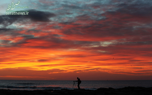 یک عکس در حال گرفتن عکس هنگام طلوع آفتاب در خلیج وایتلی انگلیس