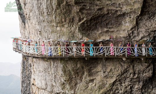زنان چینی با لباس سنتی ایستاده در امتداد یک پل ایجاد شده در امتداد یک صخره در چونگ کینگ
