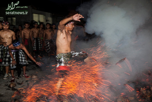 یک مرد بالیایی در حال رد شدن از آتش در طول برگزاری مراسم جنگ آتش مقدس در بالی اندونزی