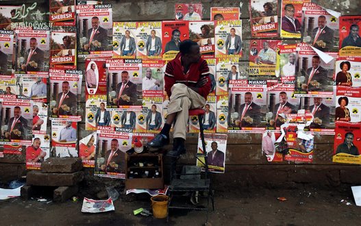 مردی نشسته در مقابل پوسترهای تبلیغاتی انتخابات در نایروبی کنیا