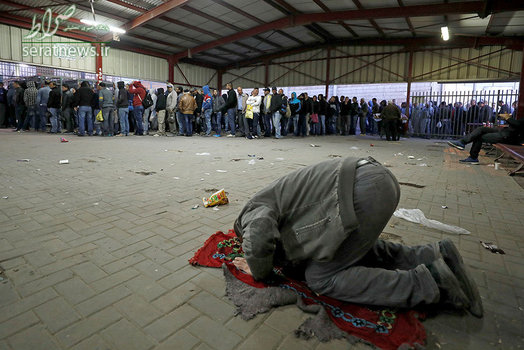 صف انتظار دهها فلسطینی در یک ایست بازرسی و نماز خواندن یک مرد