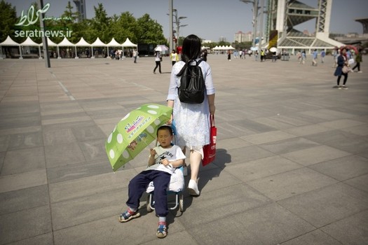 یک پسر با چتر نشسته بر روی یک سبد خرید در پکن