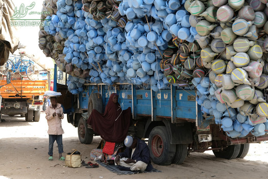 یک خانواده پناهجوی نیجریه ای در کنار یک کامیون حامل اقلام پلاستیکی در مایدوگوری