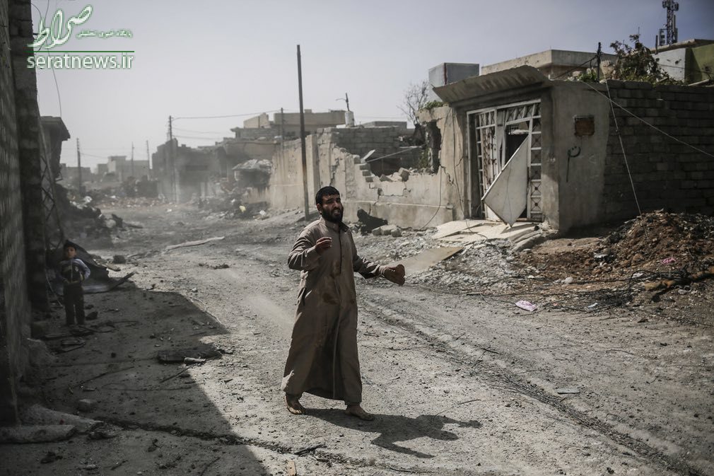یک مرد و کودک عراقی در حال فرار از خانه اش در غرب موصل