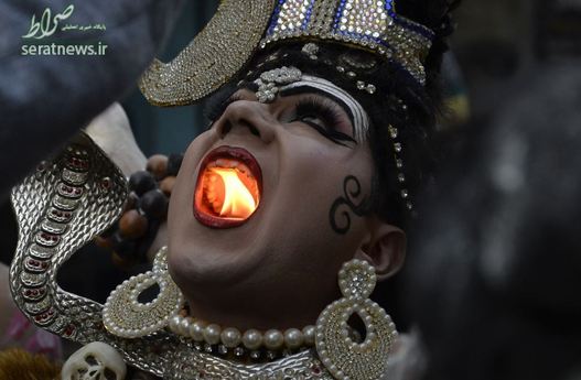 یک مرد هندی شمعی را را در یک مراسم مذهبی در دهان خود روشن کرده
